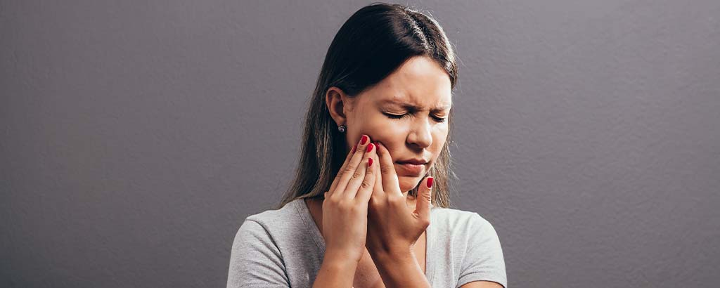 a woman rubs her jaw and wonders if she has facial infections