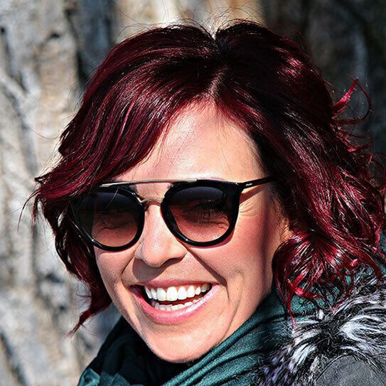 a woman smiles as she thinks about why natural teeth are better than implants